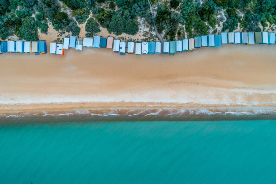 Bathing boxes along the beach with scrub behind