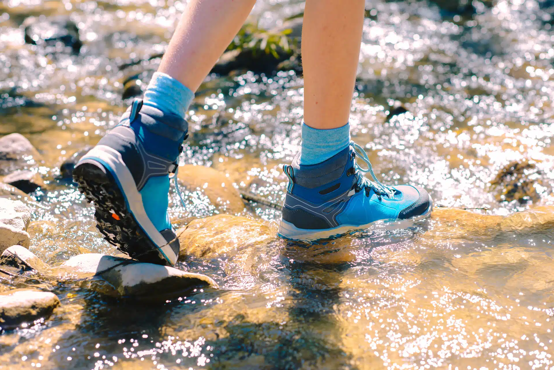 A person in blue hiking boots walking through a rocky creek. Giant step for sustainable tourism around the world