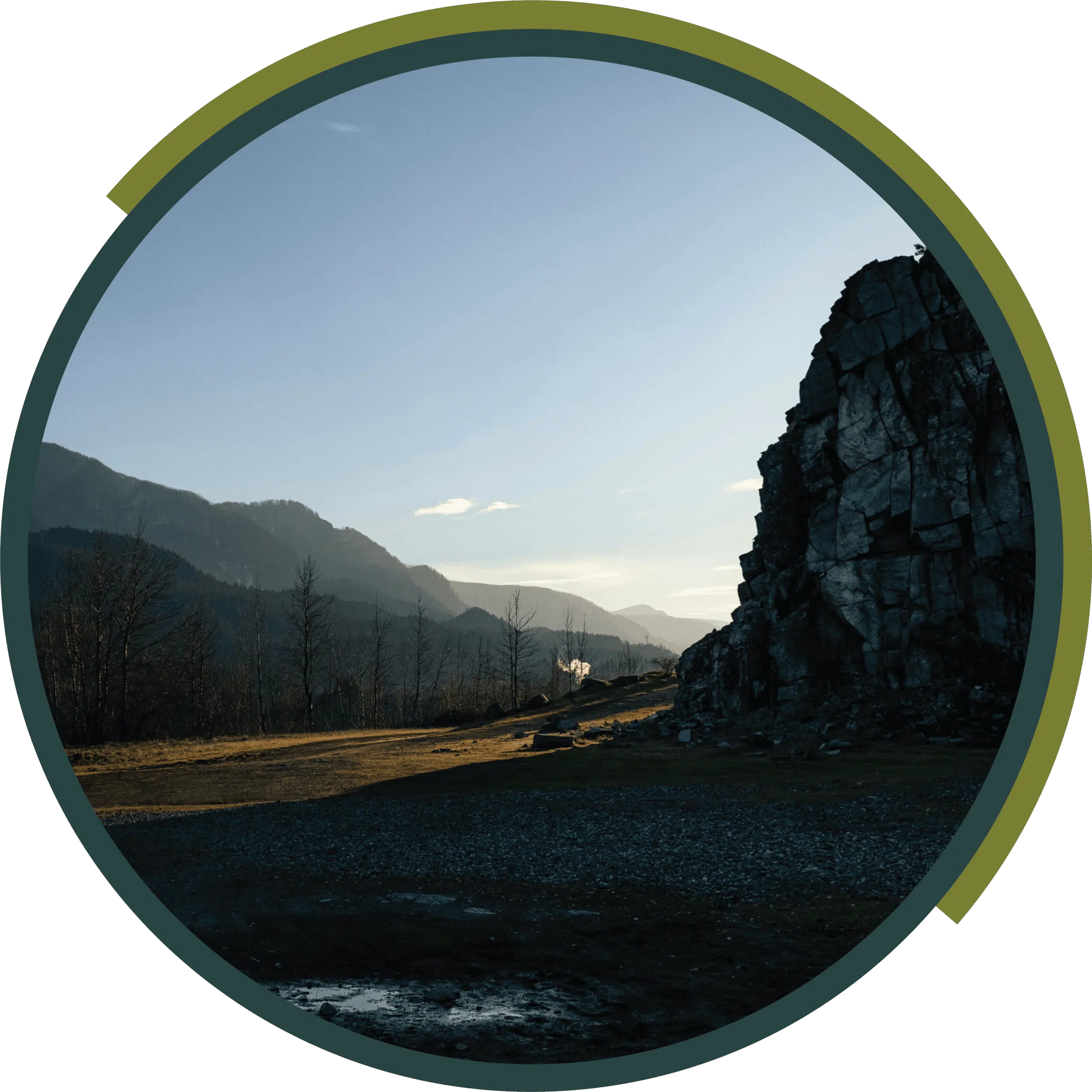 Mountain valley at sunset with a rocky cliff and golden light on the hills