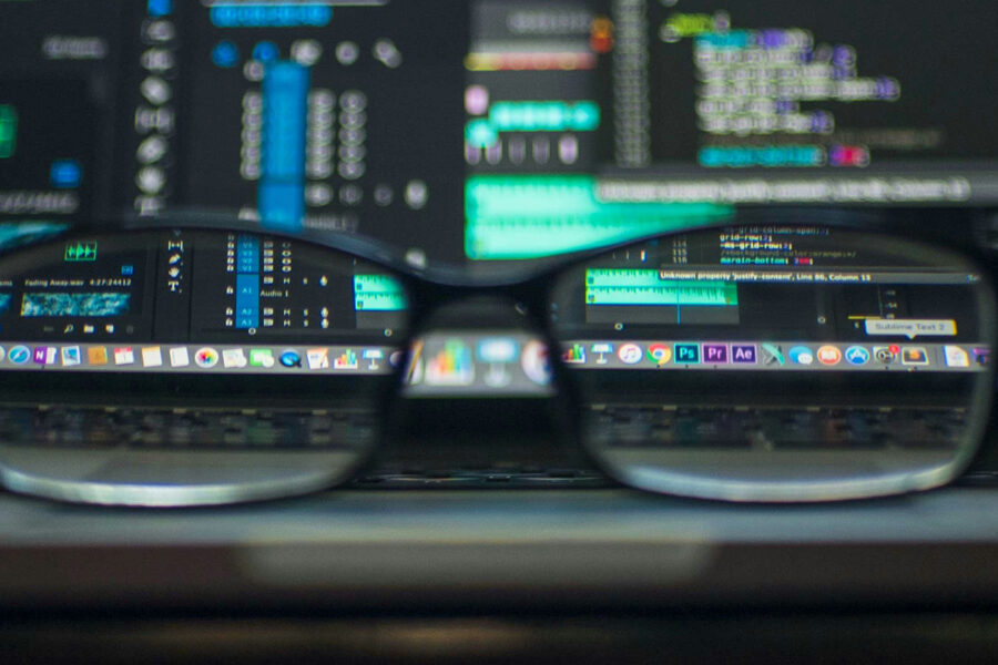 A pair of reading glasses in front of several screens showing figures and computer code for adopting the 2025 System of National Accounts